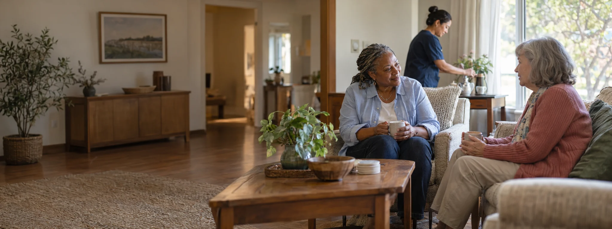 Residents and a caregiver talking in a small residential common room