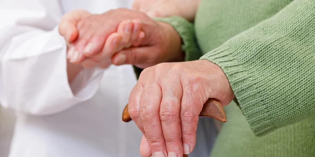 A caregiver offering support beside a resident using a cane